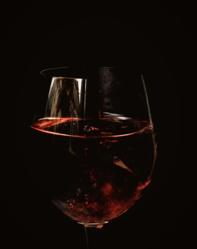 Czerwone wino wirujące w dużym kieliszku na czarnym tle